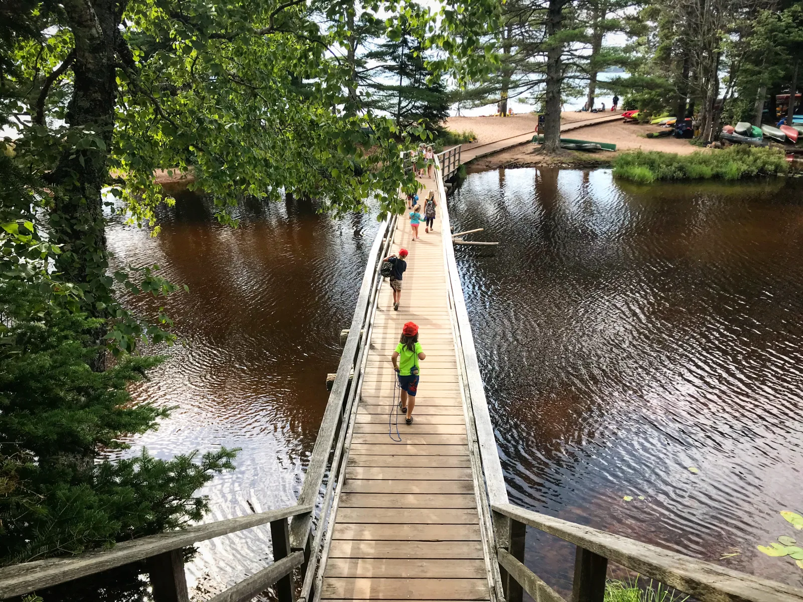 Children walking across the wooden bridge toward the shore at Big Bay Town Park