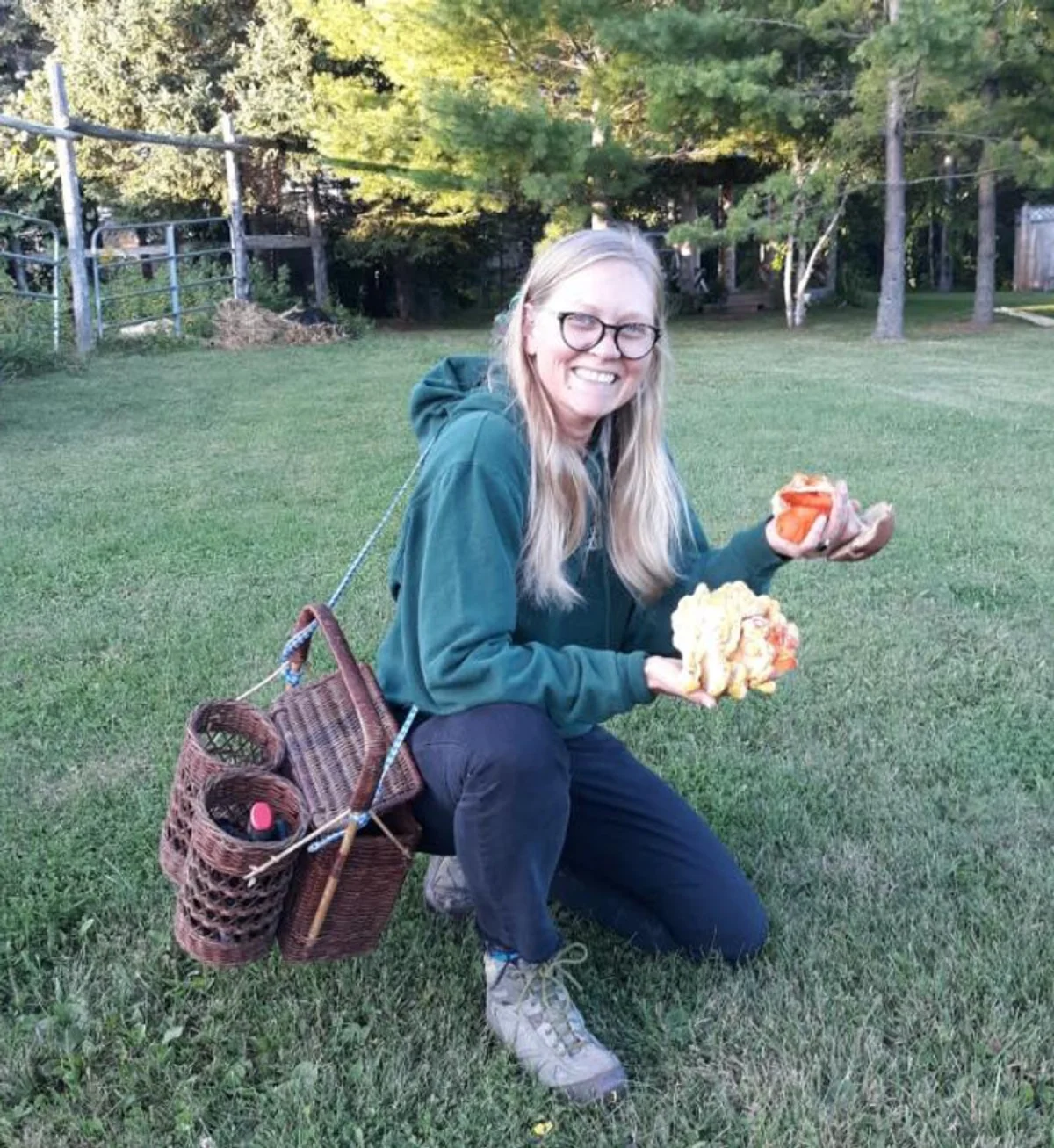 Samantha Dobson on a forest trail, holding chicken of the woods mushrooms